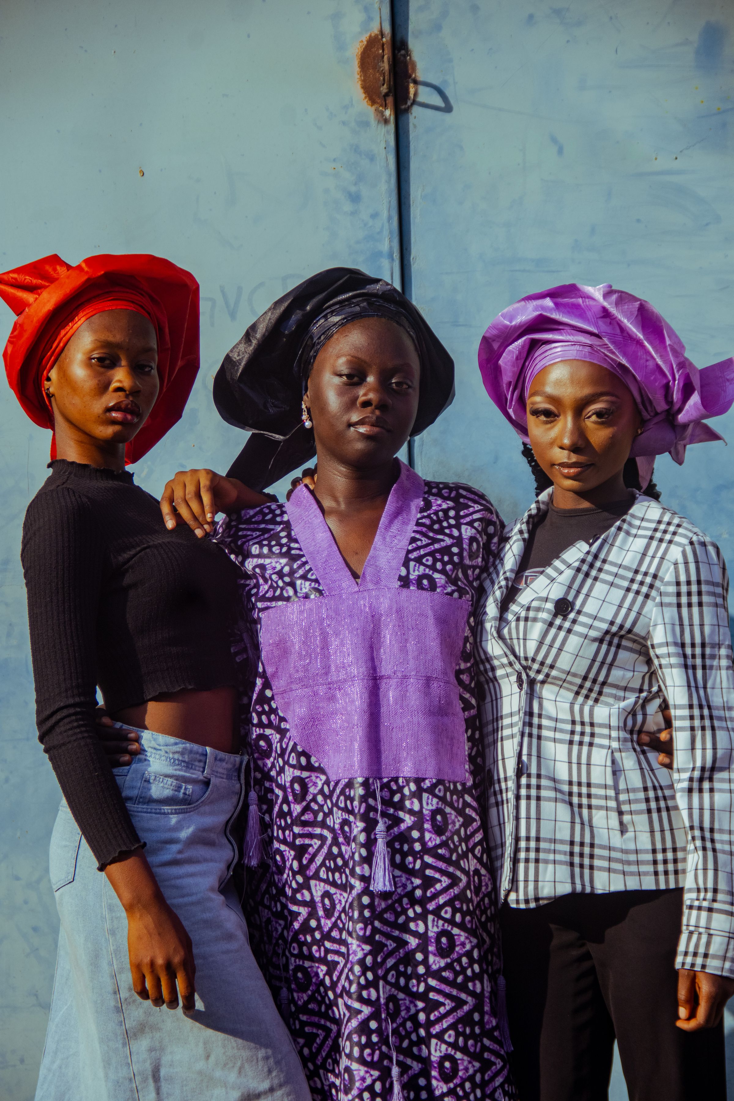 Three women modelling contemporary African fashion and colourful headwraps